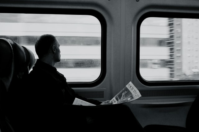 Mann sitzt im Zug und schaut aus dem Fenster